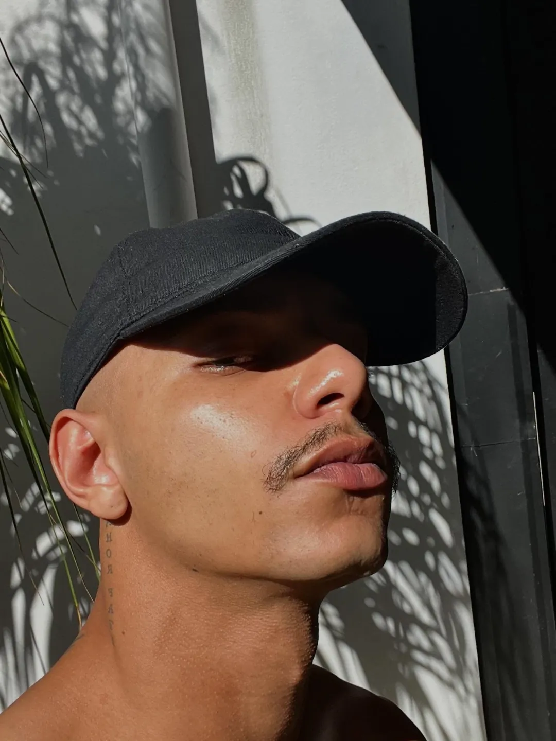 Anderson Torquato de boné, rosto iluminado pelo sol entre sombras de folhas